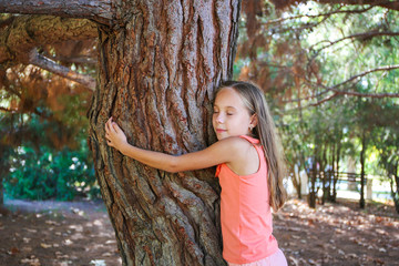 Girl hugging tree in park.
