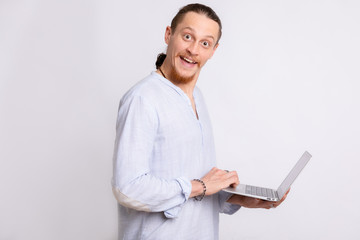 A guy in a light blue shirt holding a laptop in his hands, looking at the camera.