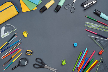 Flat lay photo of workspace desk with school accessories or office supplies on gray background.