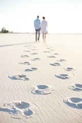 Happy couple walking holding hands at the beach