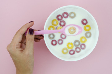 Woman holding a spoon with a fruit loop cereal