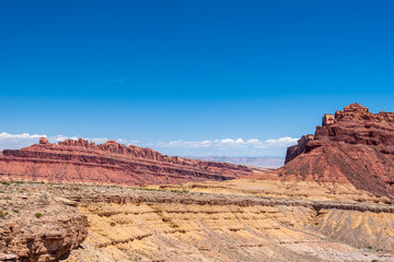 Landscape of blue sky and red and yellow massive rock formations along the San Rafael Swell in Utah