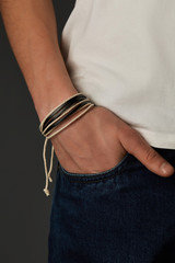 Cropped close-up shot of a male wrist with a multilayer bracelet with strings. The double-colored...