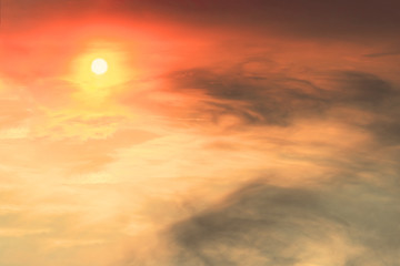 Fototapeta premium The sunset in the sky is red-orange with gray clouds in the form of stains on which the sun shines.