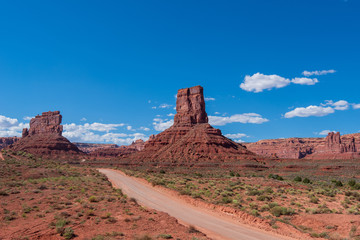 Valley of the Gods landscape of dirt road leading to red stone monoliths and buttes