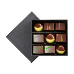 Assortment of luxury chocolate bonbons with green splashes in black box isolated on white background