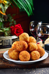 Deep-fried cheese balls laid out on a plate. Rustic style. Close-up.