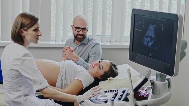 Pregnant woman and her husband on utltrasonographic examination at hospital