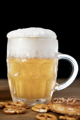 Tasty mug of beer with foam and pretzels