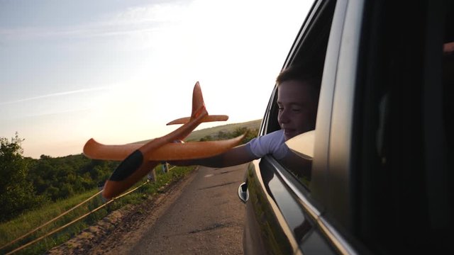 A boy with an airplane model in his hands plays traveling by car. Fantasy baby in the sun at sunset. Striving for victory and success. The concept of lifestyle and the path to success.