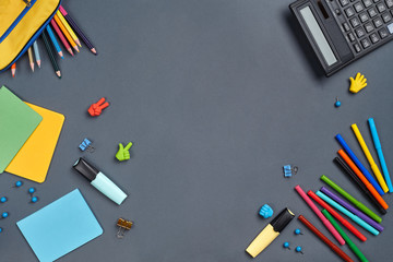 Flat lay photo of workspace desk with school accessories or office supplies on gray background.