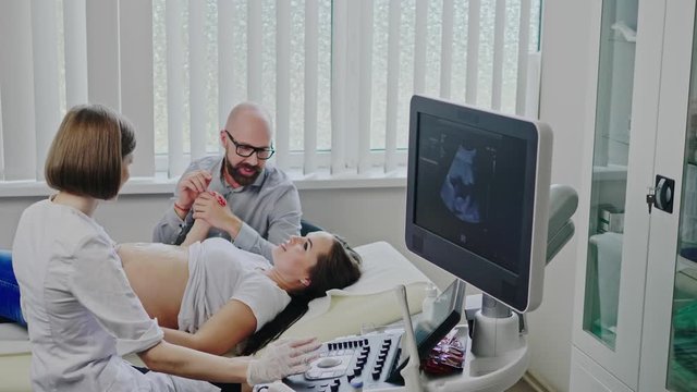 Pregnant woman and her husband on utltrasonographic examination at hospital