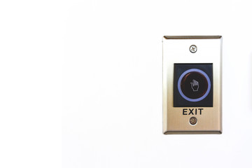 Close up exit button sensor access control with white hand symbol and blue circle isolated on white wall background. Push button switch on wall to exit with copy space.