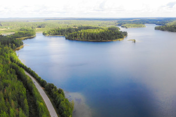 Aerial view of lake with island, road and forest on a summer sunny day in Finland. Drone photography