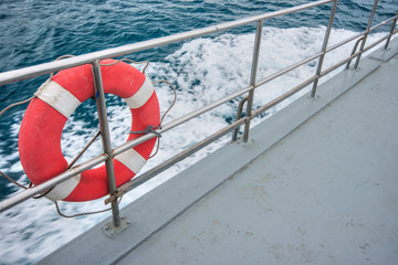 Safety white and red safety torus or lifebuoy hanging on the stainless steel fence on a boat deck...