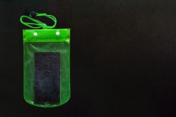 Green waterproof mobile phone case with water droplets on black texture background.PVC zip lock bag protect mobile phone or important items from water.Concept for Songkran water festival in Thailand.