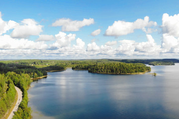 Fototapeta premium Aerial view of lake with island, road and forest on a summer sunny day in Finland. Drone photography