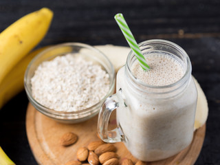 Fresh banana smoothie on a wooden table in a jar . With oatmeal and almonds