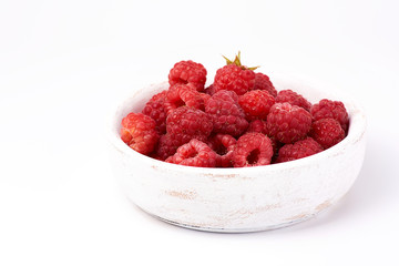 ripe red raspberries in a wooden white plate on a white background