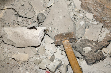 Hammer and parts of plaster after wall destruction works