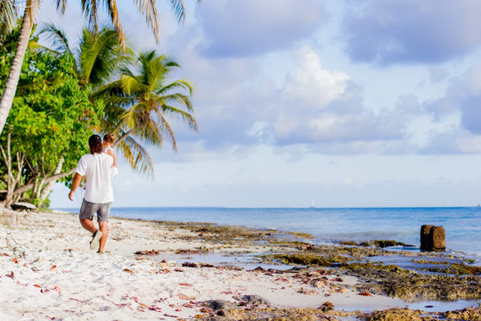 A father and daughter walk along the coast of the Caribbean Sea.