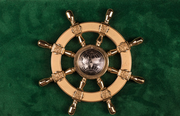 gold ship steering wheel on a green background © serikbaib