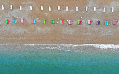 Aerial. Sea beach with colorful deck chairs. Top view from drone.