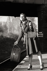 An elegant 40s lady awaits her train at Quorn and Woodhouse with her luggage.