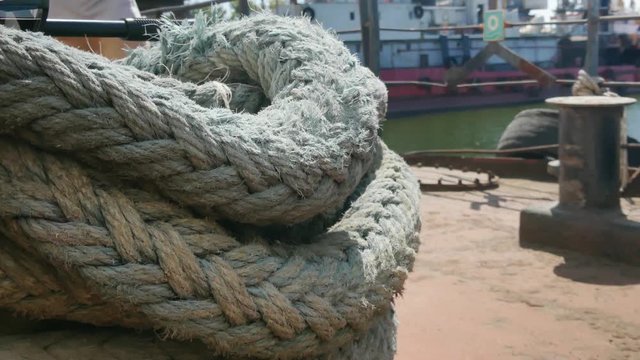 Close-up nautical knot rope tied around stake on boat or ship, boat mooring rope. Marine rope on the ship. The ship leaves the port.  Lighthouse. Mooring rope. Ship in the harbor.