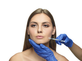 Close-up portrait of young woman on white studio background. Filling surgery procedure. Lip...