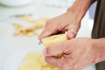 Obraz na płótnie Canvas man cutting thin slices of potato