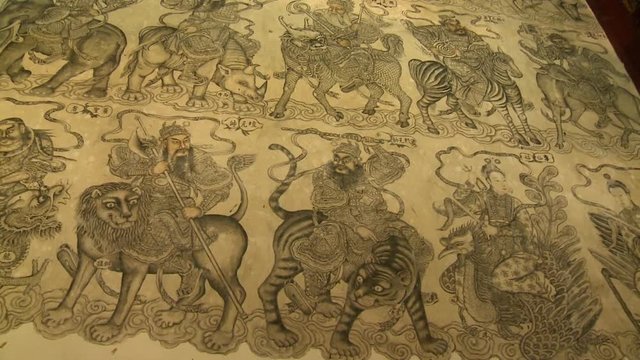 Medium low-angle panning shot of an ancient wall mural with paintings of celestial guardians Georgetown, Penang, Malaysia