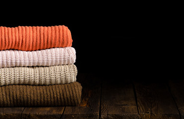 stack of clothes from knitted knitwear on a wooden background, toned image