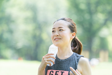 公園で運動（ヨガ）中に水分を補給する女性