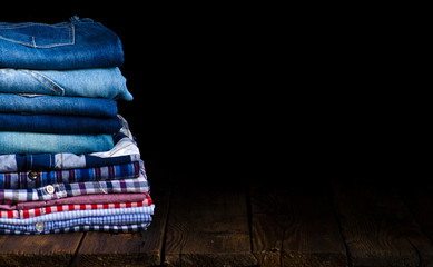 stack folded jeans and clothes cage shirt on a wooden table background