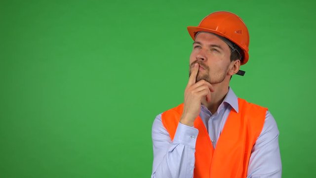 A young handsome construction worker thinks about something - green screen studio