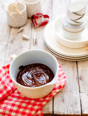 Melted chocolate in ceramic bowl on wooden background copy space