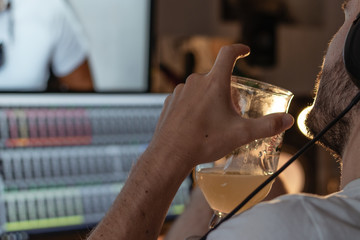 boy doing sound mixing in a studio in low light while he drinks a beer