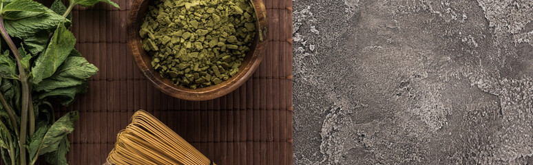 top view of green matcha tea and mint on bamboo mat on dark stone table