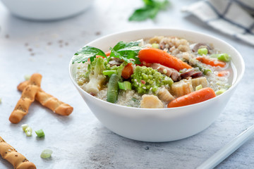 Vegetarian vegetable soup with quinoa and sesame seeds in a white bowl on the table. Tasty vegan soup, healthy eating concept.