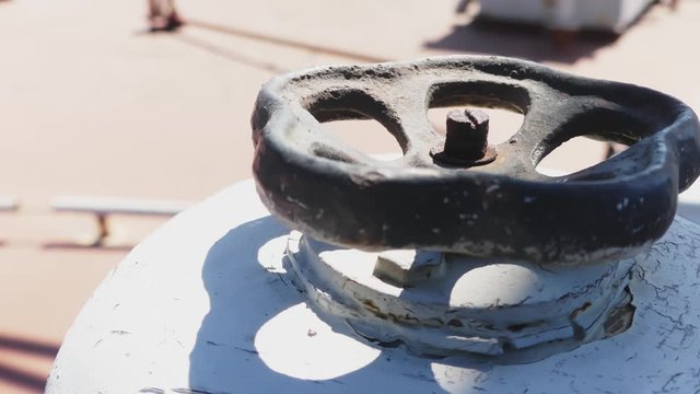Black valve in thin white rusty pipes in sea ship. Machinery and equipment of a ship.