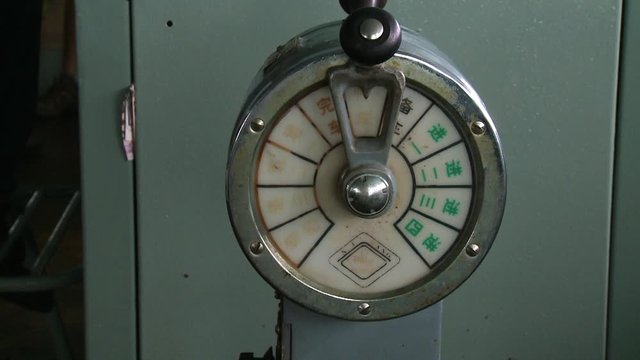 Extreme close-up low-angle front-view of a marine Engine-Gauge with Chinese writings in front of a closed metal cabinet, Langkawi Ferry Tour, Malaysia