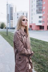 Close up street urban sexy portrait of young pretty sexual young caucasian blondie girl walking on city street in cloak and lingerie. Sexuality, beauty, fashion concept