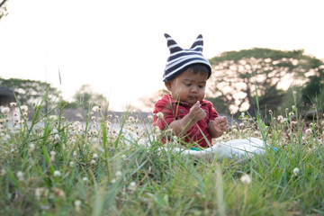 Cute happy little asian baby boy sitting at white flower garden