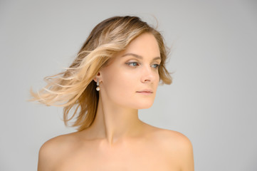 Closeup photo studio portrait of a fashionable pretty blonde young woman girl with beautiful hair on a white background. Standing right in front of the camera. Beauty, cosmetics.