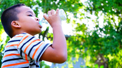 Obraz premium Asian boy drinks water from a bottle .