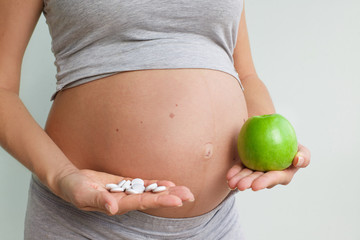 Prenatal care. Pregnant woman with pills and apple. prenatal vitamins.