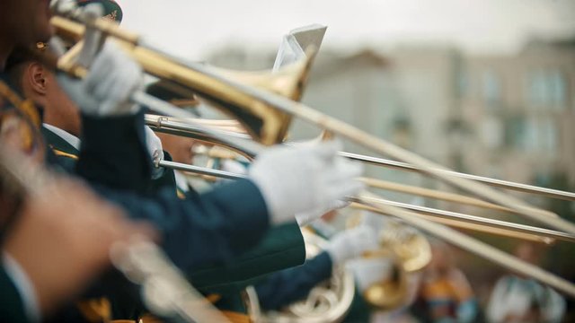 A wind instrument military parade - men in costumes playing trumpets and trombone outdoors