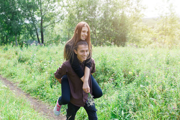 Loving multilingual couple on a walk in the Park. In love and very cheerful couple. Girl riding a...