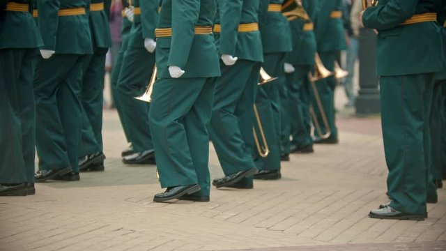 A wind instrument military parade - people in green costumes marching on the point holding instruments